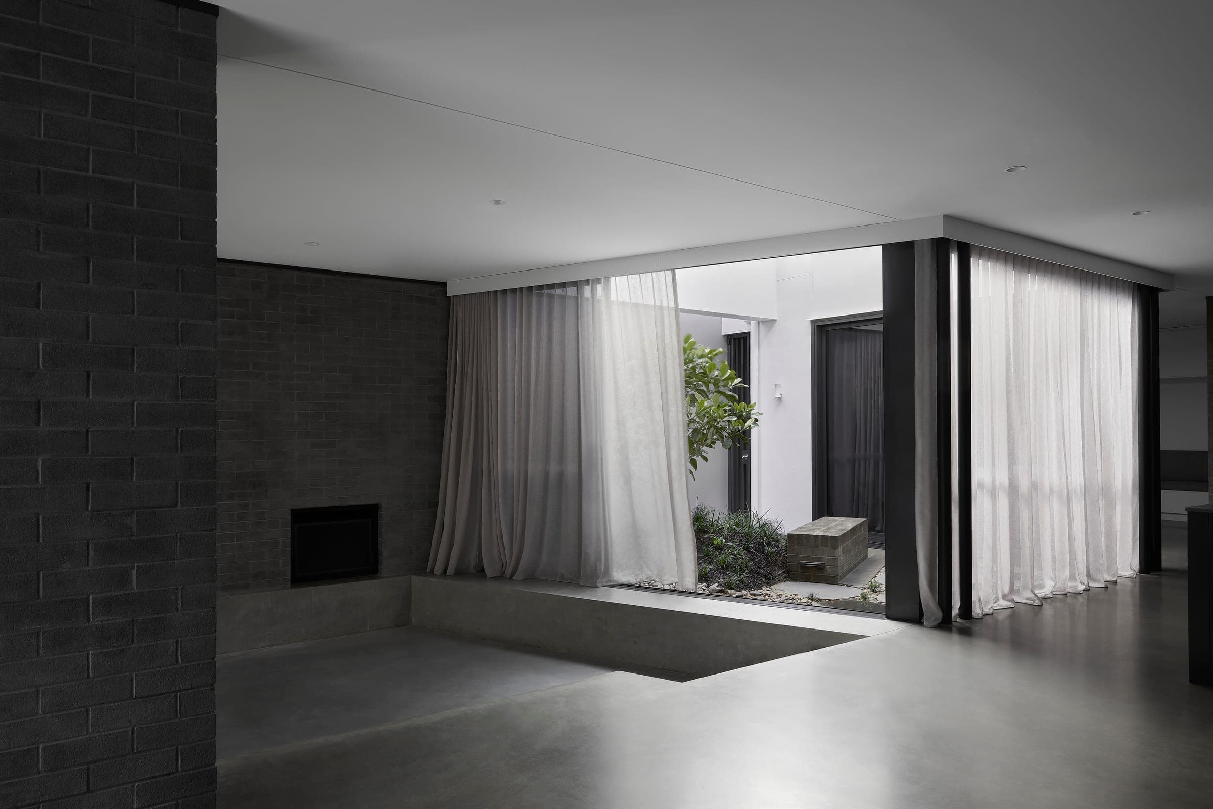 Living room looking out through sheer curtains to the planted courtyard beyond.
