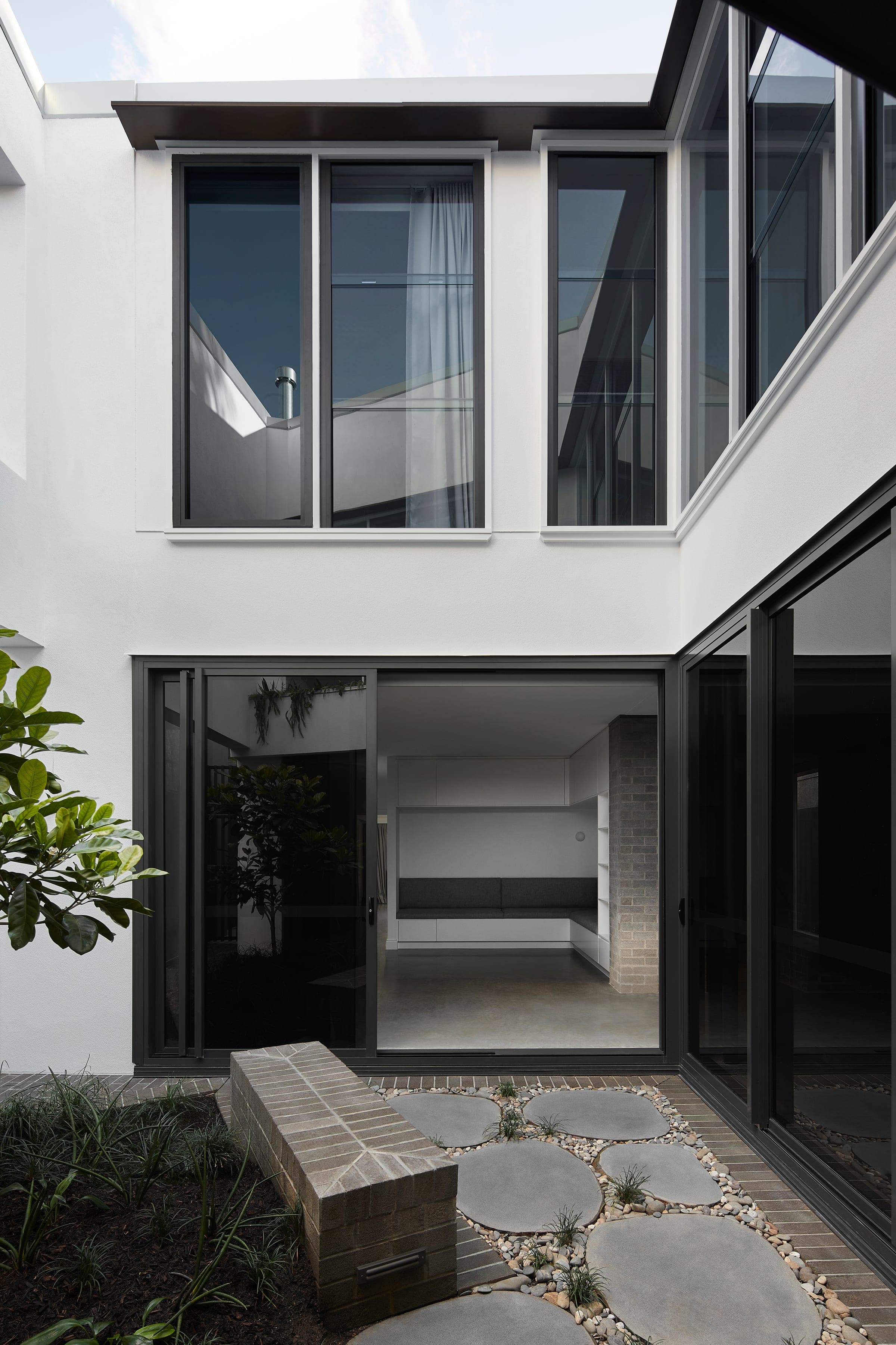 View of the central courtyard with crazy-paving stepping stones, rubber plant and the upper-floor windows above.